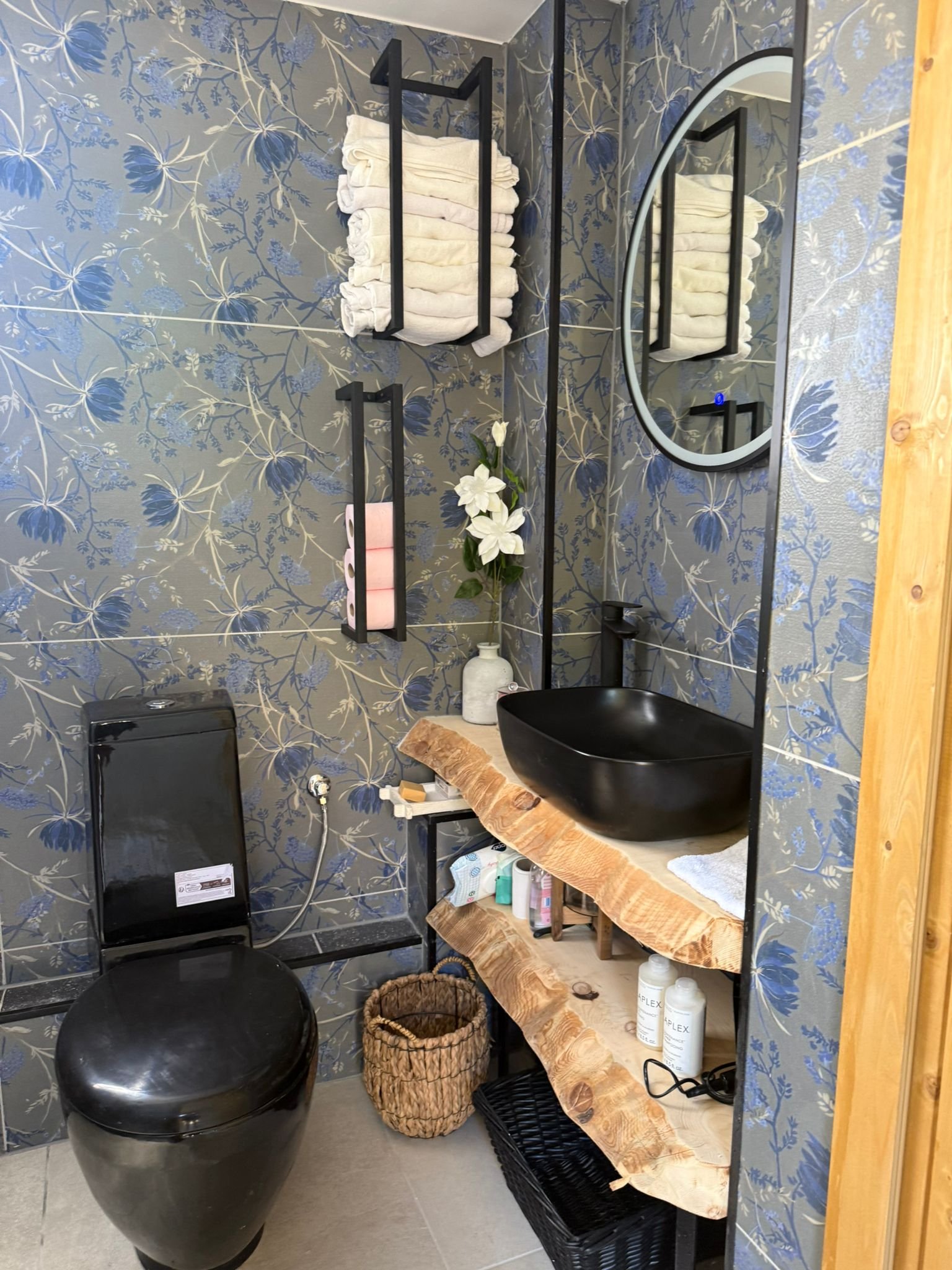 Badkamer met wastafel, spiegel en houten planken